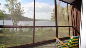 Una habitación con amplios ventanales con vistas a un lago y bosque.