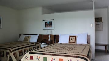 Una stanza con due letti, ognuno con una coperta, un comodino con una lampada, un quadro appeso al muro e una panca nell'angolo.