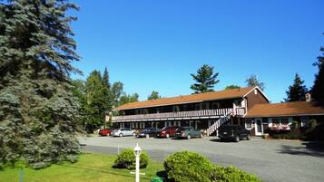 A motel with a two-story structure, a covered parking area, and a flag on the building.