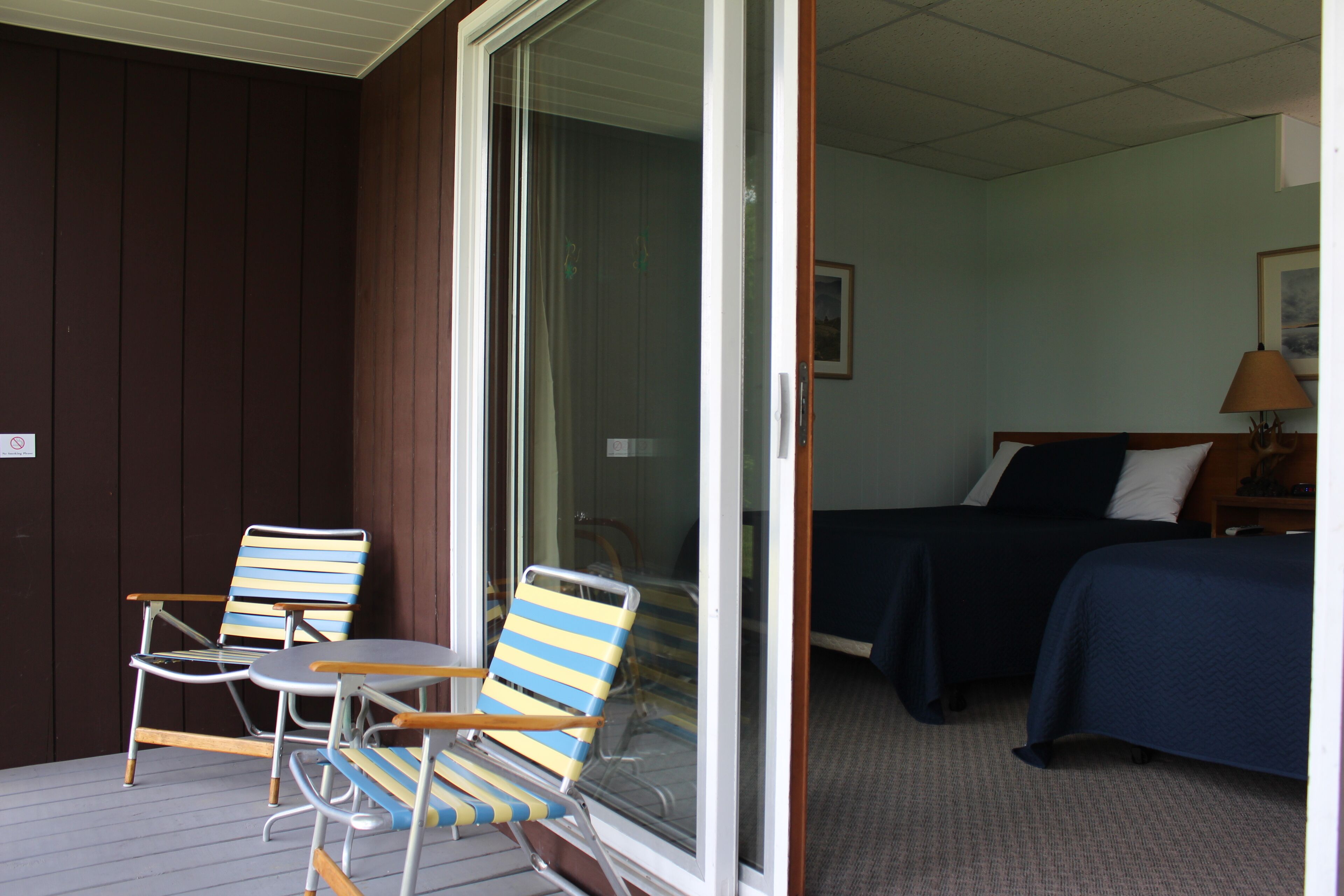 Une pièce comprenant un lit, une chaise, une table et une porte-fenêtre coulissante donnant sur un espace extérieur.