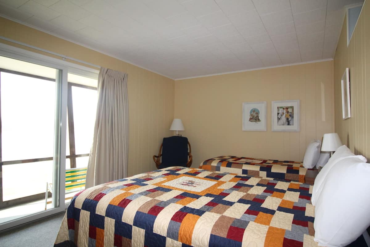 A hotel room with a large bed, a chair, a desk, and a window with curtains.
