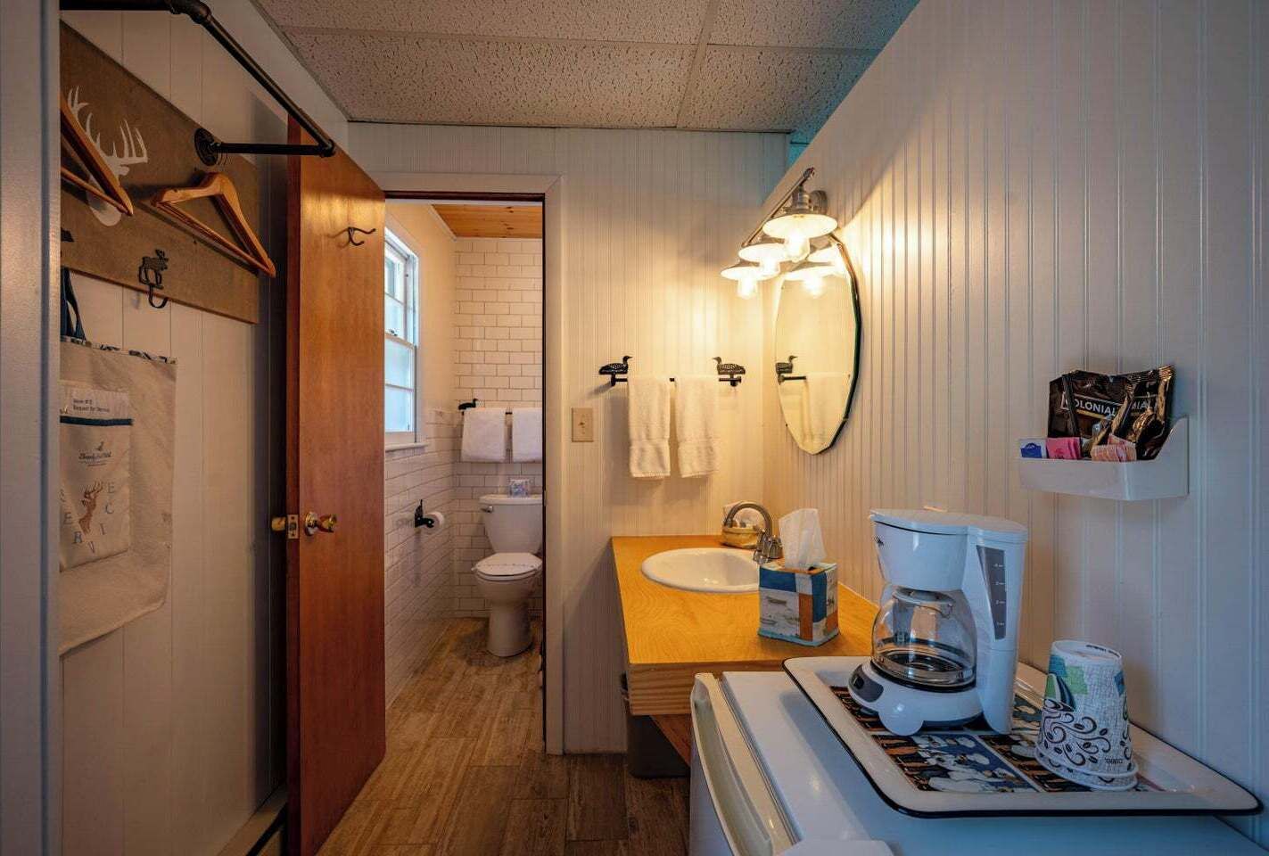 Une petite salle de bain avec un meuble-lavabo en bois, un lavabo blanc, des toilettes et une machine à café.