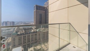 Un edificio alto con balcón de cristal que da a un paisaje urbano.