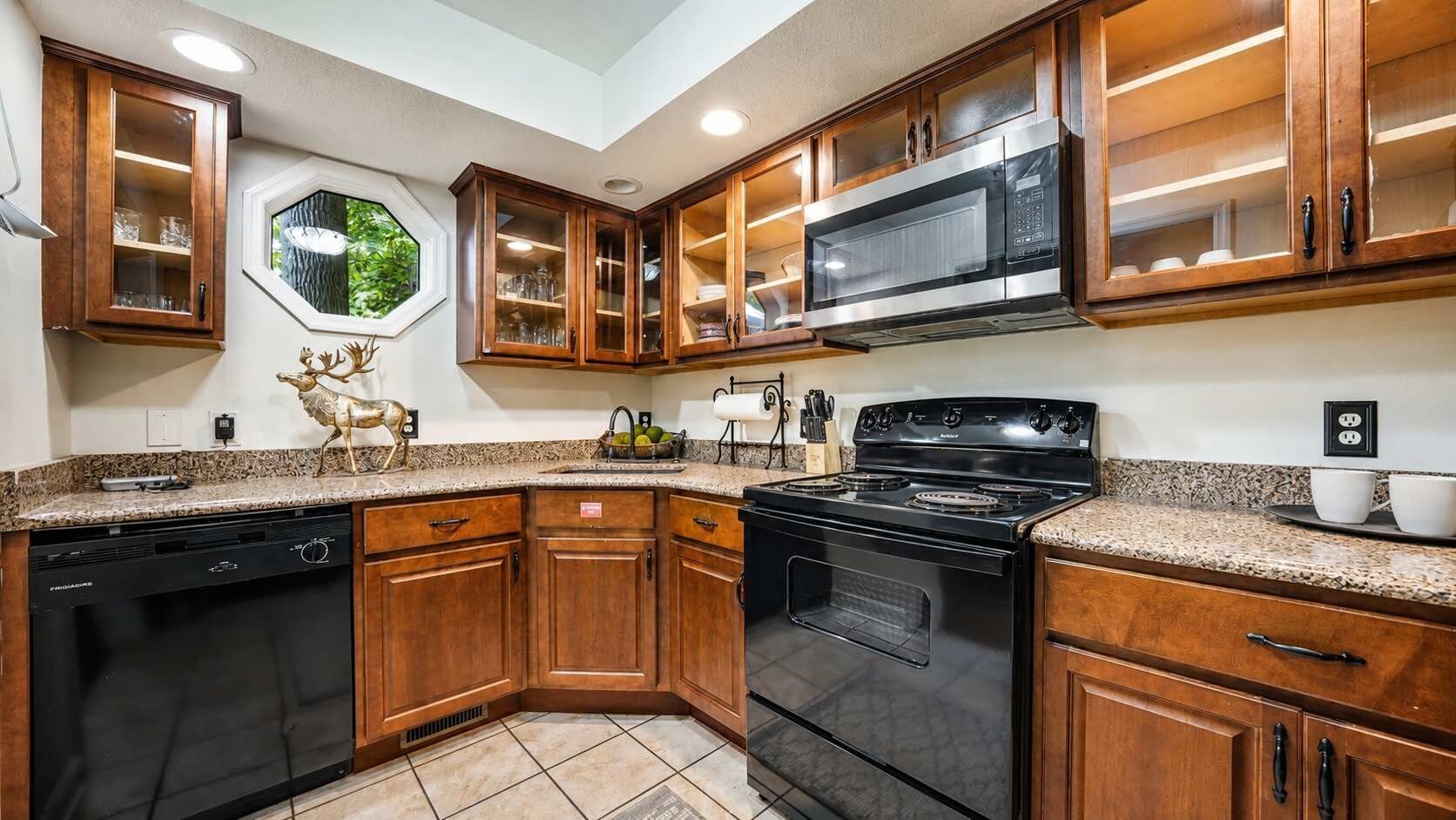 A kitchen with wooden cabinets, a stainless steel microwave, a black stove, and a dishwasher.