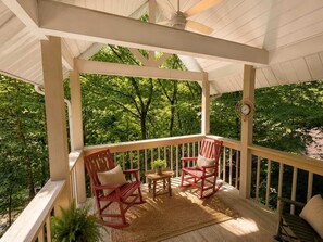 A covered porch with two rocking chairs, a small table, and a clock. - Secluded Cabin for 10 in Chalet Village + Hot Tub! (Gatlinburg)