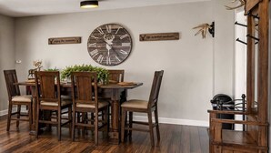 Ein Esszimmer mit Holztisch, Stühlen und einer großen Wanduhr.