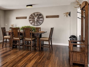 A dining room with a wooden table, chairs, and a large wall clock. - Secluded Cabin for 10 in Chalet Village + Hot Tub! (Gatlinburg)