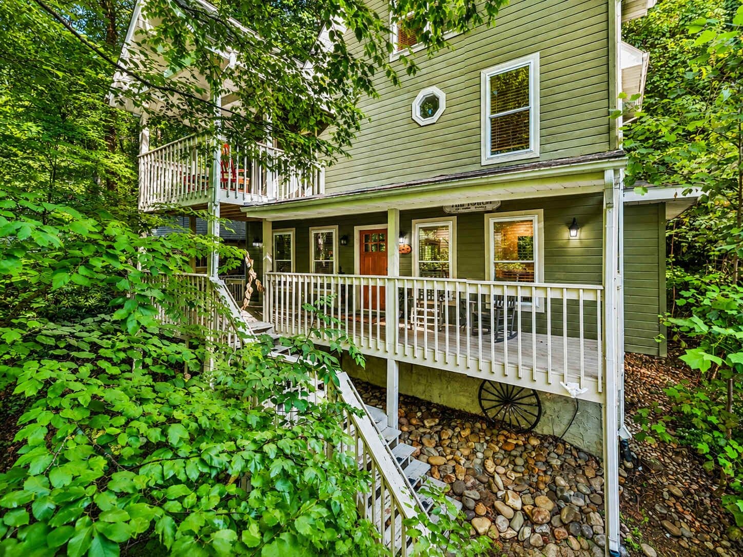 A two-story house with a porch, a staircase, and a wheelbarrow.