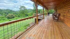 Une terrasse en bois dotée d’une balustrade, qui offre une vue sur un paysage boisé.
