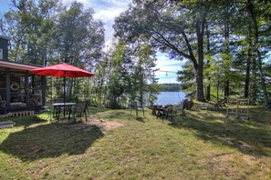 Un patio junto al lago con mobiliario exterior y un paraguas rojo.