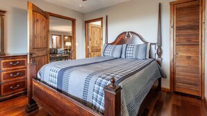 A bedroom with a wooden bed, a ceiling fan, and wooden doors. - Sunsets and Moonshine Log Cabin with Outstanding Mountain Views (Bryson City)
