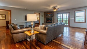 A spacious living room with a fireplace, leather sofas, and a wooden coffee table. - Sunsets and Moonshine Log Cabin with Outstanding Mountain Views (Bryson City)