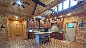 A log cabin-style kitchen with wooden floors, a central island, and built-in wooden cabinets.
