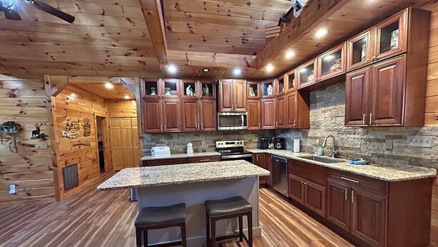 A spacious kitchen with wooden cabinets, granite countertops, and a central island with stools.