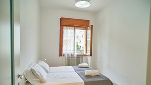 Ein kleiner, sauberer Raum mit Bett, Fenster und Heizkörper.