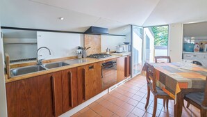 Una cocina moderna con armarios de madera, una estufa a gas, un lavamanos y un comedor con mesa y sillas.