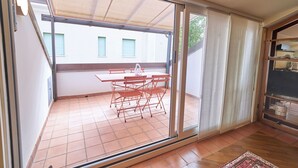 Una habitación con puerta corrediza de vidrio que da a un patio exterior con mesa y sillas.