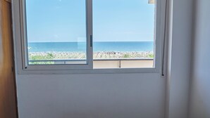 A room with a bed, a window with a view of the beach, and a towel on the bed. - Casa Clementina - One Bedroom Apartment, Sleeps 4 (Rimini)
