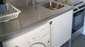 A compact kitchen with a stainless steel sink, a gas stove, and a built-in washing machine. - Casa Clementina - One Bedroom Apartment, Sleeps 4 (Rimini)