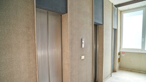An interior corridor with a closed elevator door, a light switch, and a fire safety sign on the wall. - Casa Clementina - One Bedroom Apartment, Sleeps 4 (Rimini)