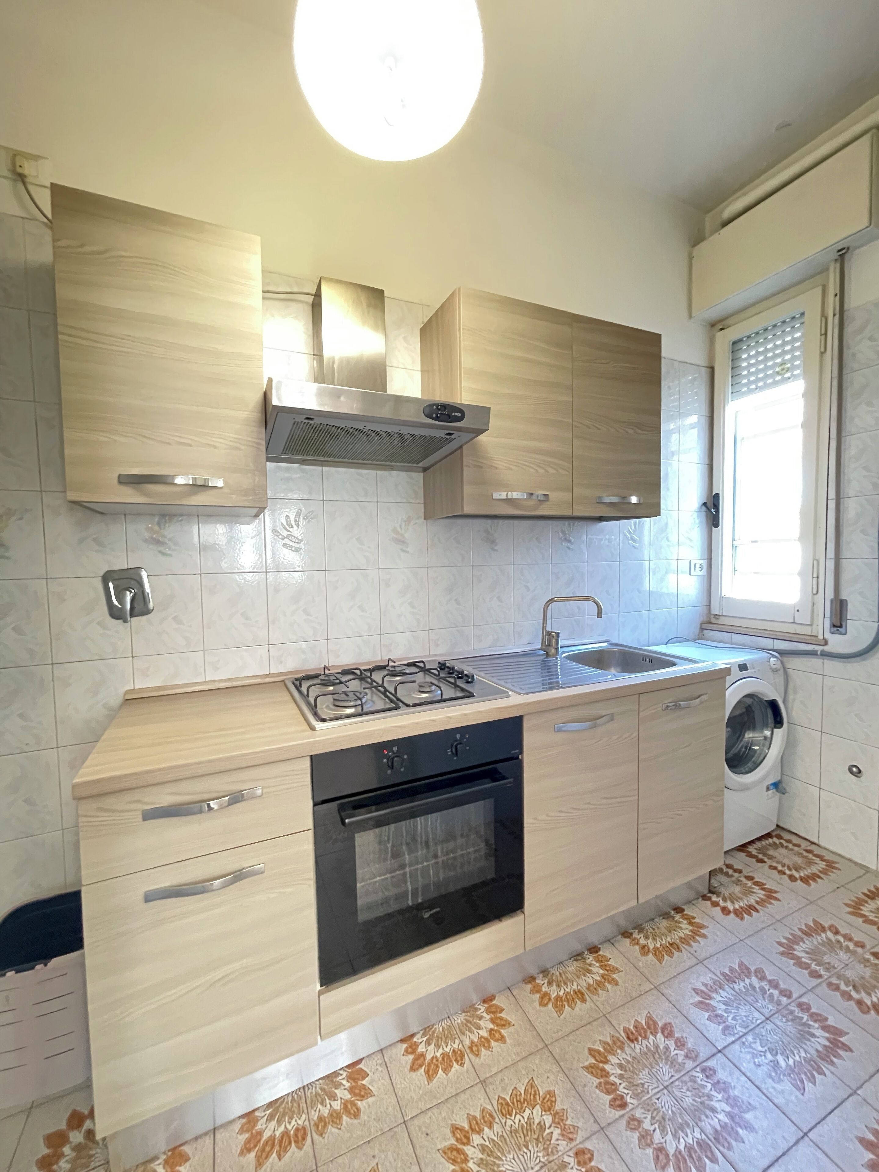 A modern kitchen with a gas stove, oven, sink, and built-in washing machine.