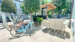 A patio area with a blue bicycle, wicker chairs, and a pergola.