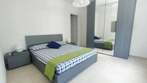 A modern bedroom with a bed, nightstands, and a mirror.