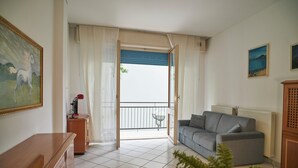 Un salon avec un canapé gris, un meuble en bois et un tableau accroché au mur.
