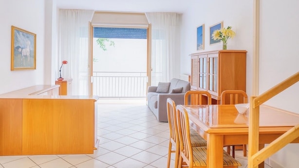 Un vaste espace de vie comprenant une table à manger en bois, un canapé et un balcon avec vue.