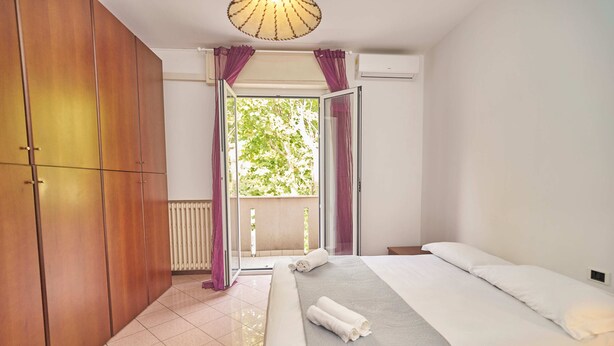 Un dormitorio con cama, armario y ventana con cortinas.
