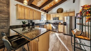 A modern kitchen with wooden cabinets, stainless steel appliances, and a granite island.