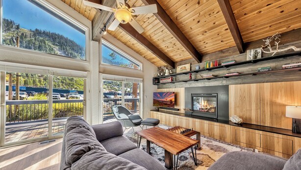 A modern living room with a fireplace, large windows, and a view of a mountainous landscape.