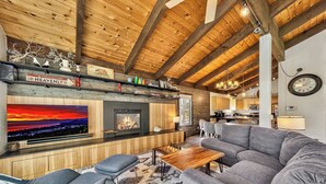 A cozy living room with a fireplace, a large TV, and a comfortable sofa.