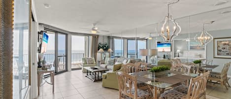 A spacious living area with a dining table, chairs, and a balcony with a view.