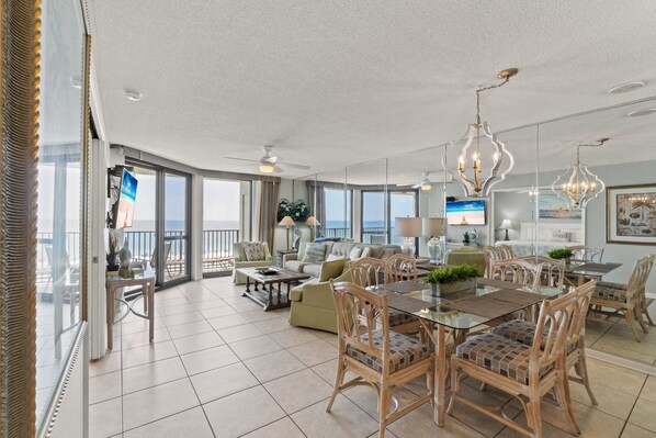 A spacious living area with a dining table, chairs, and a balcony with a view.