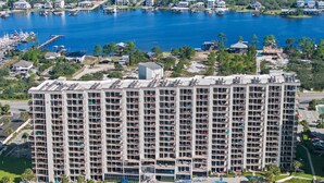 Un hotel moderno de gran altura con varios balcones, una piscina y un puerto deportivo al fondo.