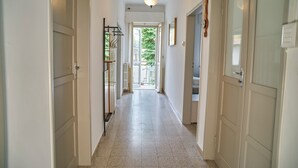 A hallway with white doors, a hanging light fixture, and a view of the outdoors. - Casa Renata - Three Bedroom Apartment, Sleeps 5 (Rimini)
