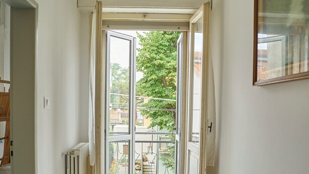 A narrow hallway with a radiator on the left, a door at the end leading to a balcony, and a framed picture on the right wall. - Casa Renata - Three Bedroom Apartment, Sleeps 5 (Rimini)
