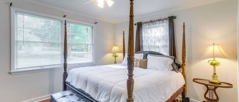 A four-poster bed with a wooden headboard, a bedside table with a lamp, and a bench.