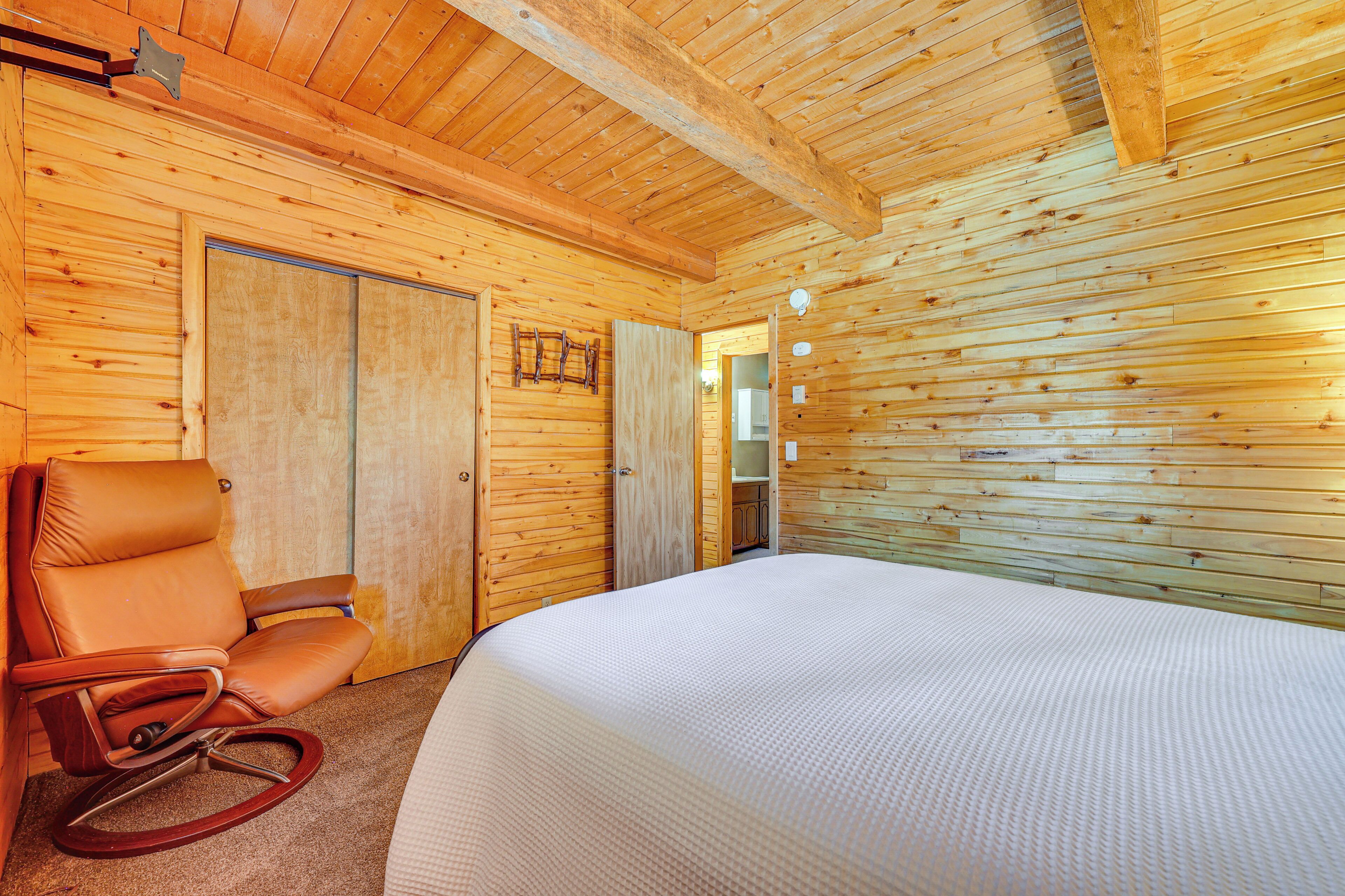 Un interior de madera con una cama, un sillón mecedora y una puerta de madera.