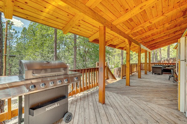 Une terrasse extérieure couverte, équipée d’un barbecue et d’un espace salon.