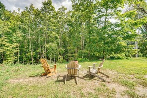 A forested area with three Adirondack chairs and a fire pit. - Studio w/ Trail Access ~ 10 Mi to Brattleboro! (Vernon)