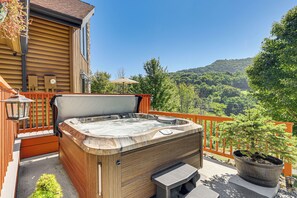 A hot tub on a balcony with a view of a forested hillside. - Deck & Mtn Views: Log Cabin By Snowshoe Mountain! (Slaty Fork)