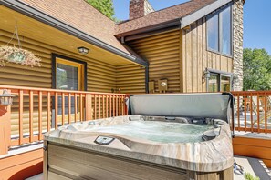 A hot tub on a wooden deck with a stone wall and a window. - Deck & Mtn Views: Log Cabin By Snowshoe Mountain! (Slaty Fork)