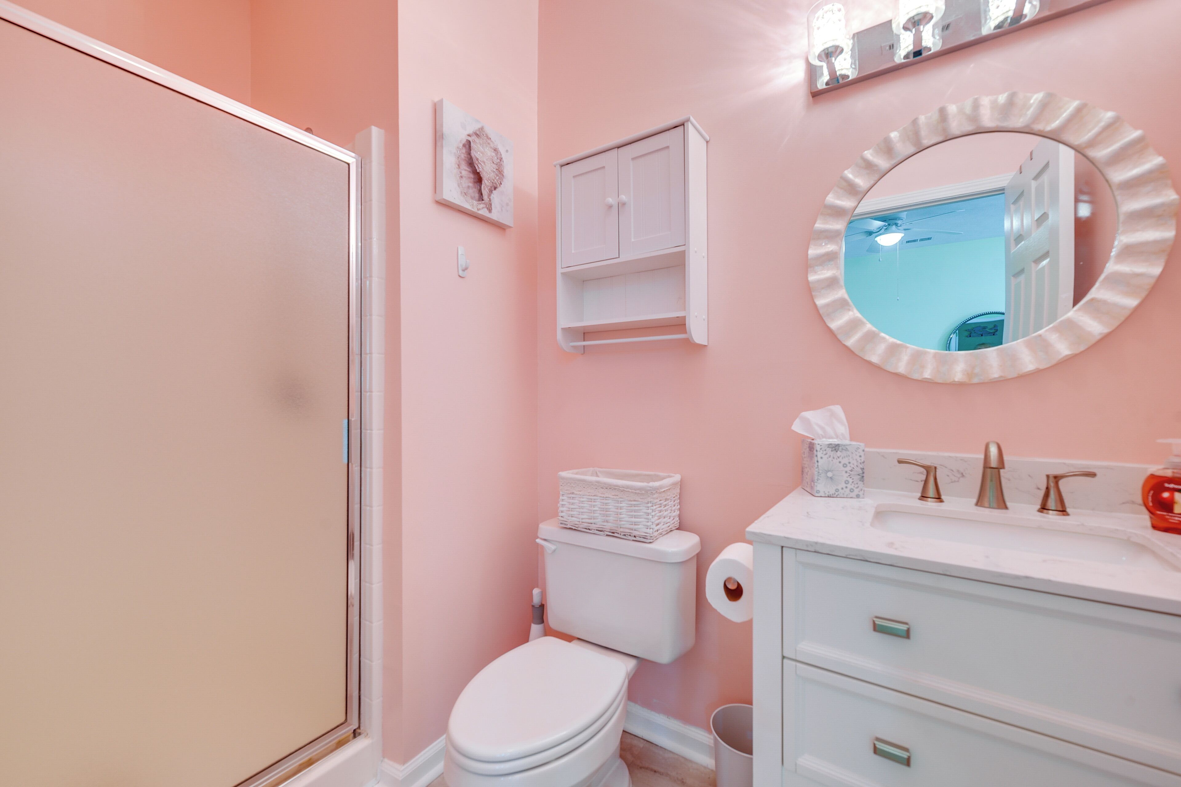 A bathroom with a toilet, sink, and mirror.