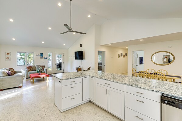 A spacious kitchen with white cabinetry, granite countertops, and a ceiling fan. - Lake Champlain Retreat w/ Grill, Fire Pit! (Chazy)