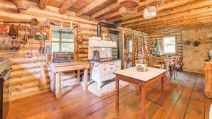 A rustic cabin interior with wooden floors, a dining area, a kitchen with vintage appliances, and a Christmas tree. - 1800s Romantic Cabin! Fireplace + 3 Jacuzzi Tubs (Paris)