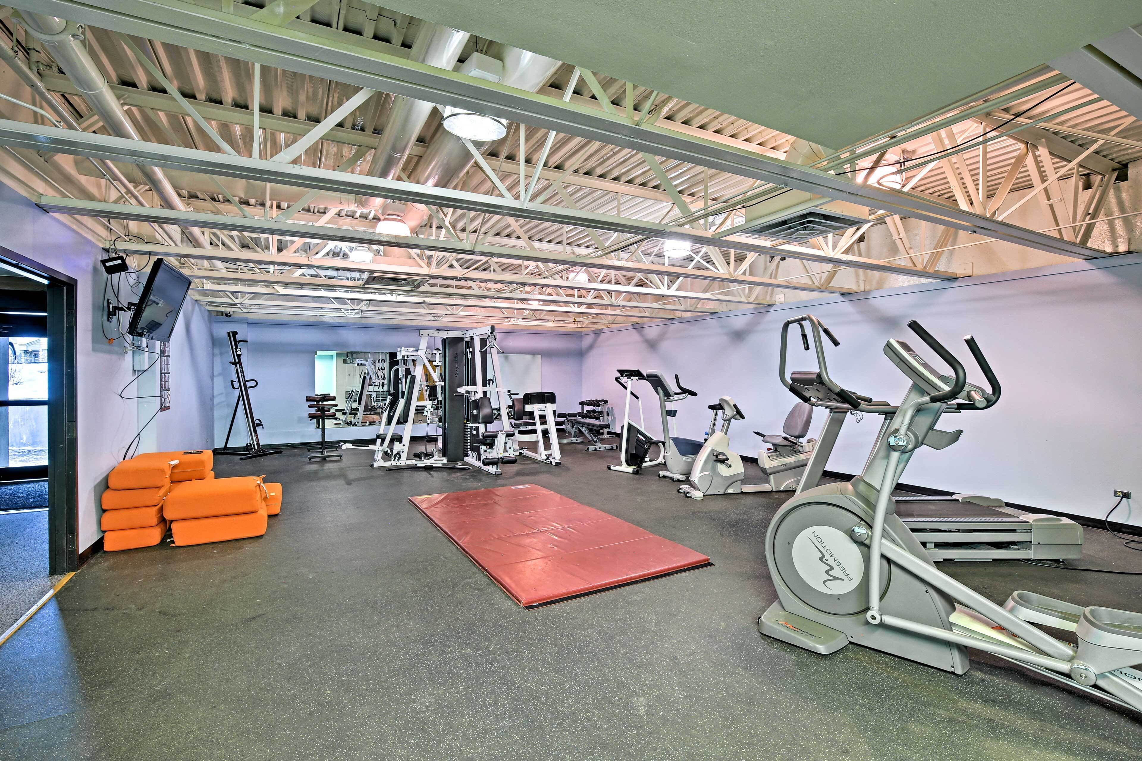 Une salle de sport équipée de matériel d’exercice, avec un tapis rouge et des bancs orange.