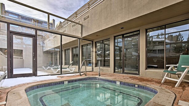 An indoor swimming pool with clear glass walls, a tiled edge, and a sun chair. - Ski Retreat w/ Hot Tub Access in Winter Park! (Winter Park)