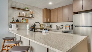 A modern kitchen with a large island, wooden cabinets, and stainless steel appliances. - Ski Retreat w/ Hot Tub Access in Winter Park! (Winter Park)